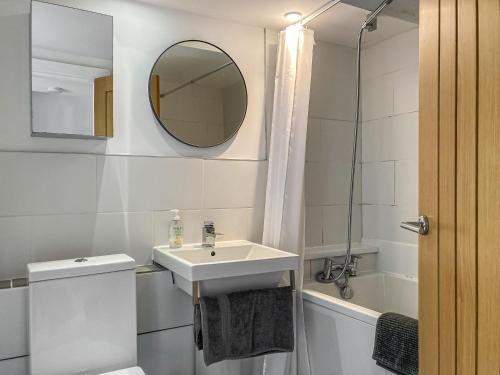 a white bathroom with a sink and a mirror at The Old Workshop in Appledore