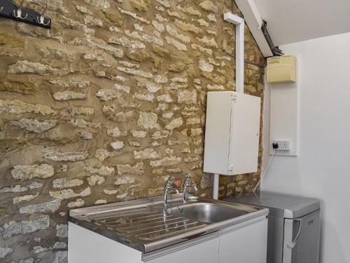 a kitchen with a sink and a stone wall at Swallowdale Cottage in Levisham