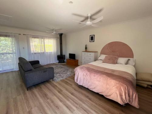 a bedroom with a bed and a chair and a ceiling fan at Bluebell Cottage in Beechmont