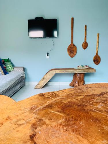 a living room with a wooden table and guitars on the wall at Portuá Chalés in São Miguel dos Milagres