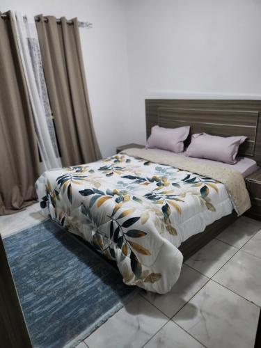 ein Schlafzimmer mit einem Bett mit einer Decke und Kissen in der Unterkunft Résidence Mami in Dakar