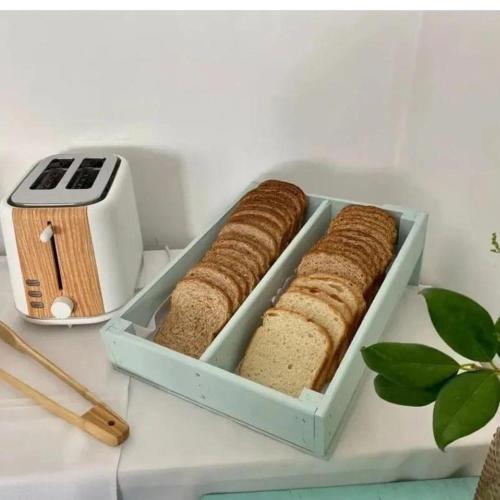 two slices of bread in a blue container next to a toaster at Hotel Kelman in Perito Moreno