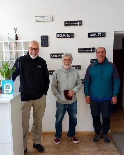 three men standing next to a wall with signs at Hotel Kelman in Perito Moreno