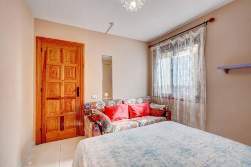 a bedroom with a bed and a couch and a window at Compostella Beach - 2 bedroom in Arona