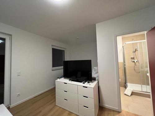 a white room with a television and a dresser with a shower at LUX Apartments in Mörfelden-Walldorf