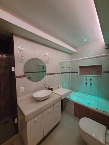 een badkamer met een wastafel, een spiegel en een bad bij Apê Turquesa, 190 m da praia do Leme in Rio de Janeiro