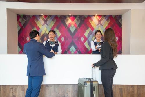 Un groupe de personnes se tenant autour d'un comptoir avec une femme dans l'établissement Hotel Clarion Suites Guatemala, à Guatemala