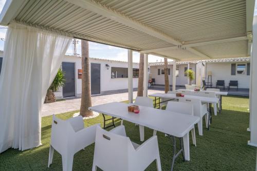 a row of tables and white chairs under a marquee at Bungalows Buda Beach in Sanlúcar de Barrameda