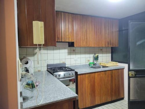 a kitchen with wooden cabinets and a stove top oven at Amplio y lindo departamento. in Arequipa