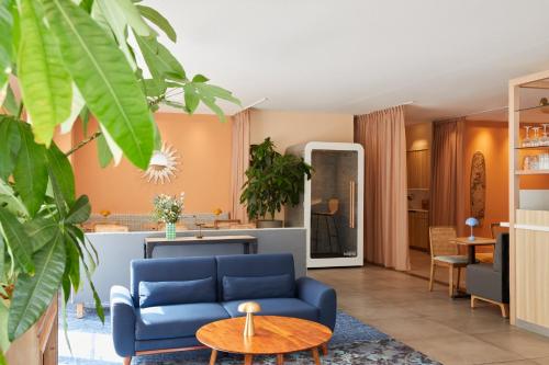 a living room with a blue couch and a table at Hotel Indigo Bordeaux Centre Chartrons by IHG in Bordeaux