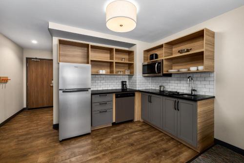 a kitchen with a white refrigerator and wooden cabinets at Candlewood Suites - Layton - Salt Lake City by IHG in Layton