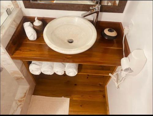 a bathroom with a sink and towels on a wooden shelf at Utila Water Sports Deluxe Apt in Utila