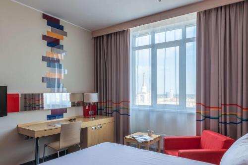 a hotel room with a bed and a desk and a window at Park Inn by Radisson Volgograd in Volgograd
