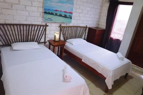 dos camas sentadas una al lado de la otra en una habitación en Hostal Maresia, en Data de Posorja
