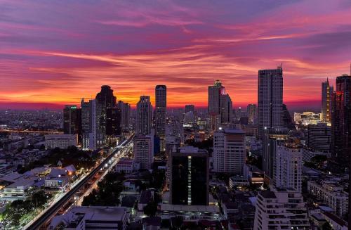 a city skyline with a sunset in the background at InterContinental Bangkok Sukhumvit by IHG in Bangkok