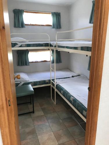 a room with three bunk beds and a window at Prom Central Caravan Park in Foster