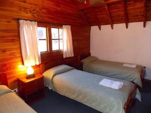 a room with two beds and a window in a cabin at Cabañas Luz de Luna in San Martín de los Andes