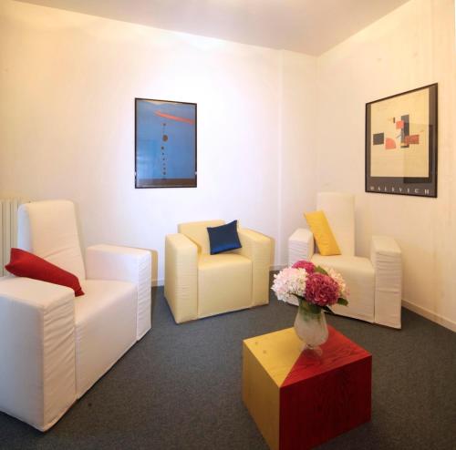 a room with white chairs and a vase of flowers on a table at Il Cascinalenuovo in Asti