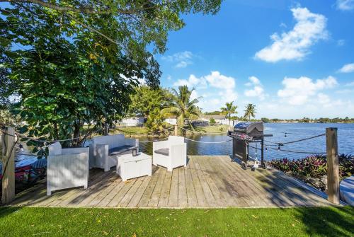 a wooden dock with chairs and a grill on the water at Dior Lake Front Villa With Infinity Pool & Hot Tub in Miami Gardens