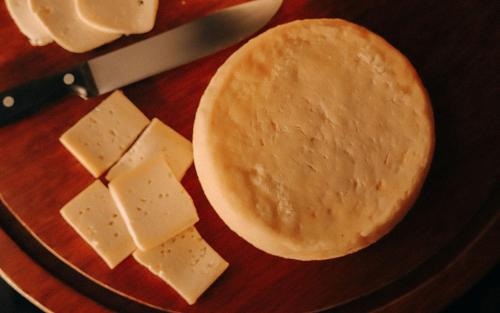 um prato com queijo, uma panqueca e uma faca em Pousada Quinta dos Cabeças em Capitólio