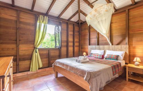 a bedroom with a bed in a room with wooden walls at L'îlot Fruits Guadeloupe in Trois-Rivières