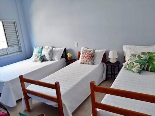 ein Zimmer mit 2 Betten und einem Stuhl darin in der Unterkunft Apartamento charmoso no centro de Ubatuba in Ubatuba