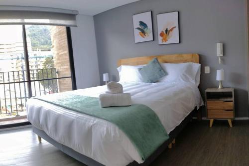a bedroom with a large bed and a large window at Nuevo! Apartamento Oasis Central in Bogotá