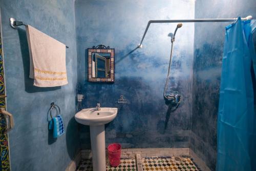 a blue bathroom with a sink and a shower at Riad Qamar Fez in Fès