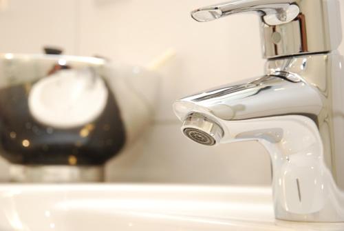 a white bathroom sink with a faucet and a lamp at Münsterländer Hof in Cloppenburg