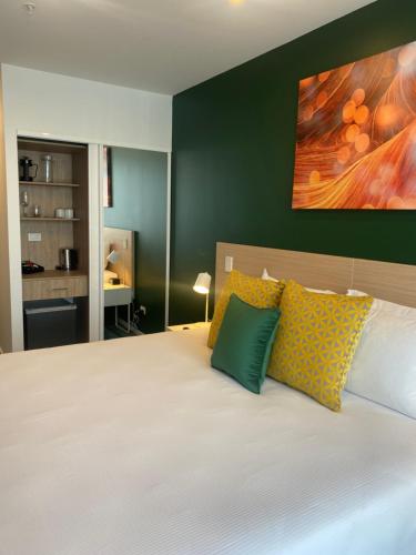 a bedroom with a bed with yellow and green pillows at La Quinta by Wyndham Ellerslie Auckland in Auckland