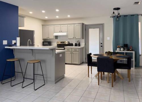 a kitchen with white cabinets and a table and chairs at Chic, Quiet 2BR 2BA Near Shops & Restos! in McAllen