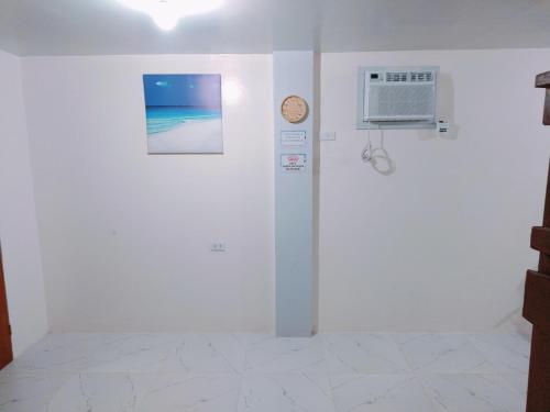 um quarto branco com um relógio na parede em Rendezvous Beach Resort - Cabongaoan em Tambobong