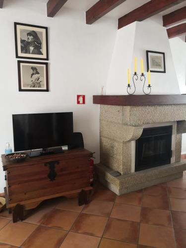 a living room with a fireplace and a television at Casa do Suberco in Nazaré