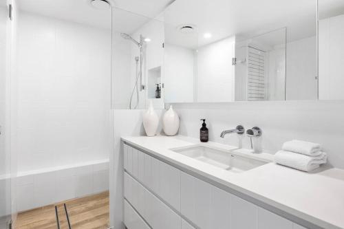 a white bathroom with a sink and a mirror at Commodore Apartment 5, Noosa Heads in Noosa Heads