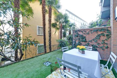 a table and chairs in a garden with palm trees at Soleil 5 Apt with Green Terrace in Lugano Center -By EasyLife Swiss in Lugano