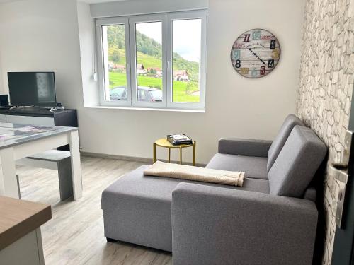 a living room with a couch and a clock on the wall at Cocon lumineux près des pistes in La Bresse