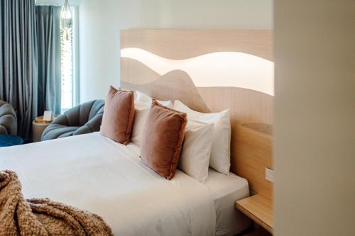 a bedroom with a bed with white sheets and pillows at CitySide Hotel Tauranga in Tauranga