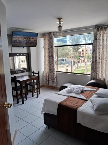 een slaapkamer met een bed, een tafel en een raam bij LAS ARTES INN in Lima