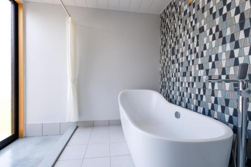 a bathroom with a white tub and a tile wall at VILLA SOUTH COAST SHIMA in Hamajima