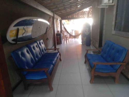 a room with two blue chairs and a surfboard on the wall at Casa dos Cardoso in Maricá