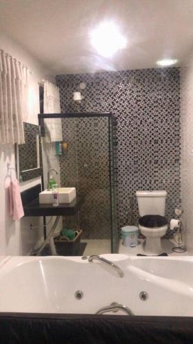 a bathroom with a bath tub and a toilet at Casa dos Cardoso in Maricá