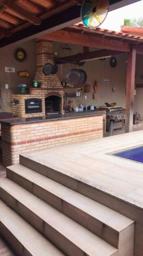 a patio with a fireplace and an outdoor kitchen at Casa dos Cardoso in Maricá