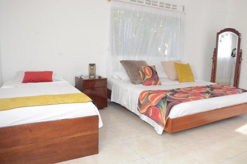 a bedroom with two beds and a mirror at VILLA ALEJANDRIA - CABAÑA LAMARIQUITA-CABAÑA ORQUIDEA-CABAÑA CARAMBOLa in Mariquita