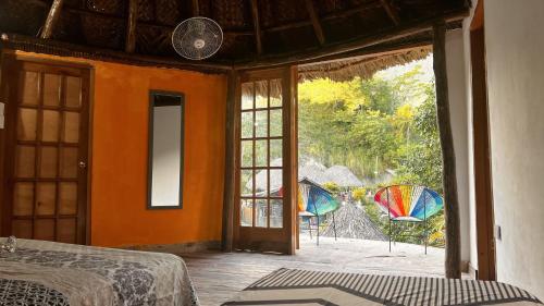 a bedroom with an open door to a patio with chairs at Tawaca ecohotel in Santa Marta