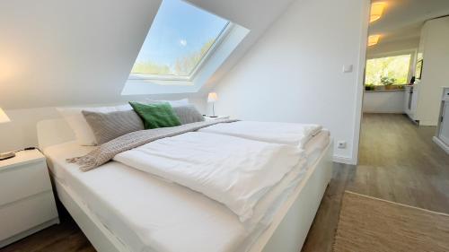 a white bed in a room with a window at Kapitänshaus FeWo 3 in Cuxhaven
