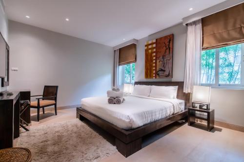 une chambre avec un lit, un bureau et des fenêtres dans l'établissement Poppy Beachfront Residence, à Rawai Beach