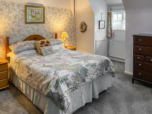 a bedroom with a bed and a dresser at Granary Cottage in Torquay