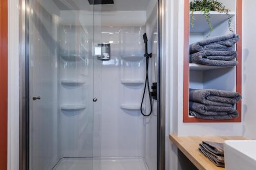 La salle de bains est pourvue d'une douche et de serviettes sur les étagères. dans l'établissement New calm & relaxing Tiny House w deck near ZION, à Apple Valley