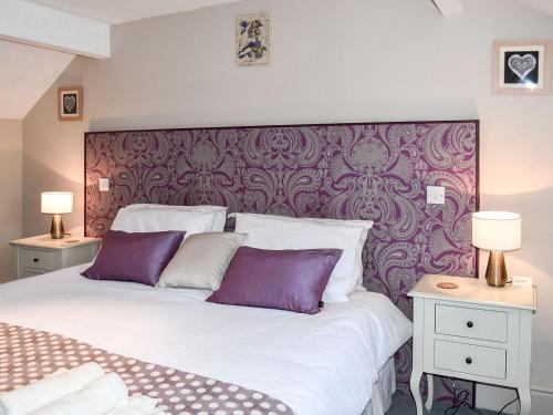 a bedroom with a large bed with purple and white pillows at Cartws Blaenparc Coach House - Uk41031 in Mydroilin