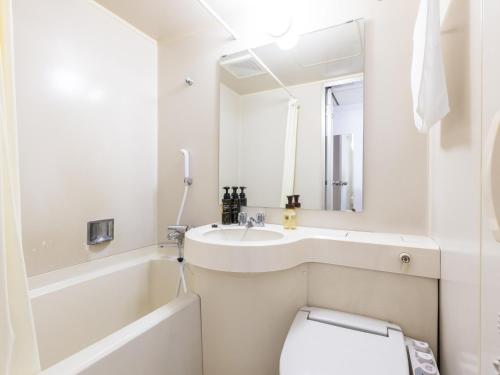 Hotel Wing International Sukagawa في Sukagawa: حمام أبيض مع حوض ومرحاض